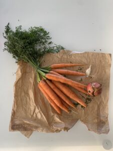 Carote, aglio e melagrana su di un foglio di carta da pane